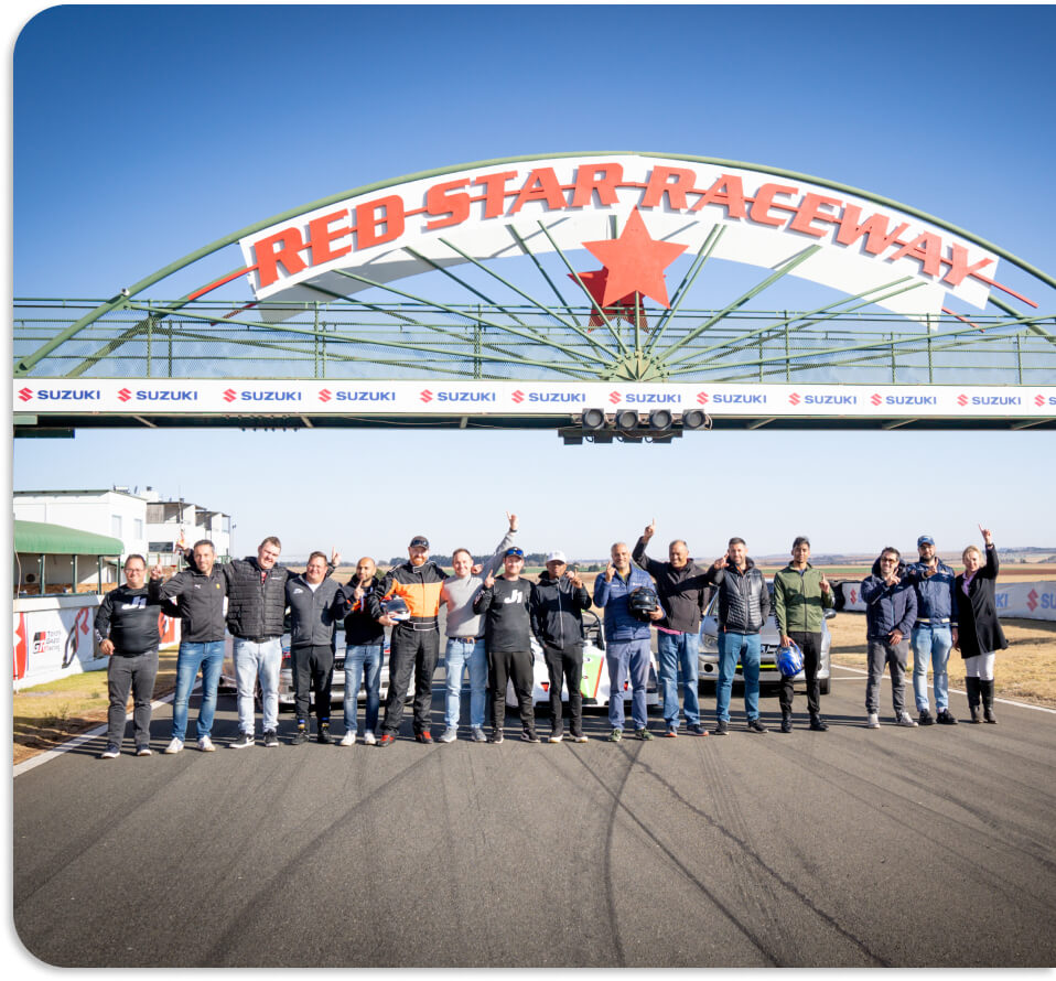 A group of track drivers standing in a line at Red Star Raceway